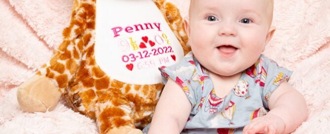 a baby sits with a personalised giraffe toy