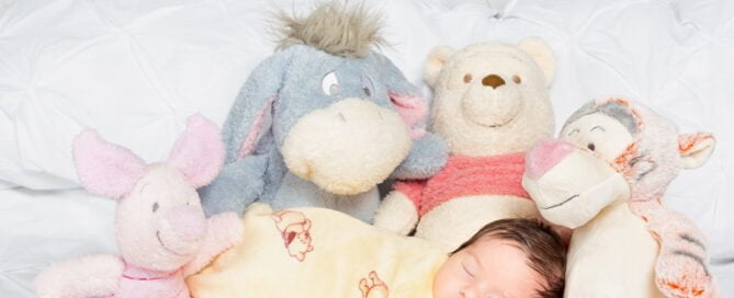 a newborn and a a host of Winnie the Pooh stuffed toys