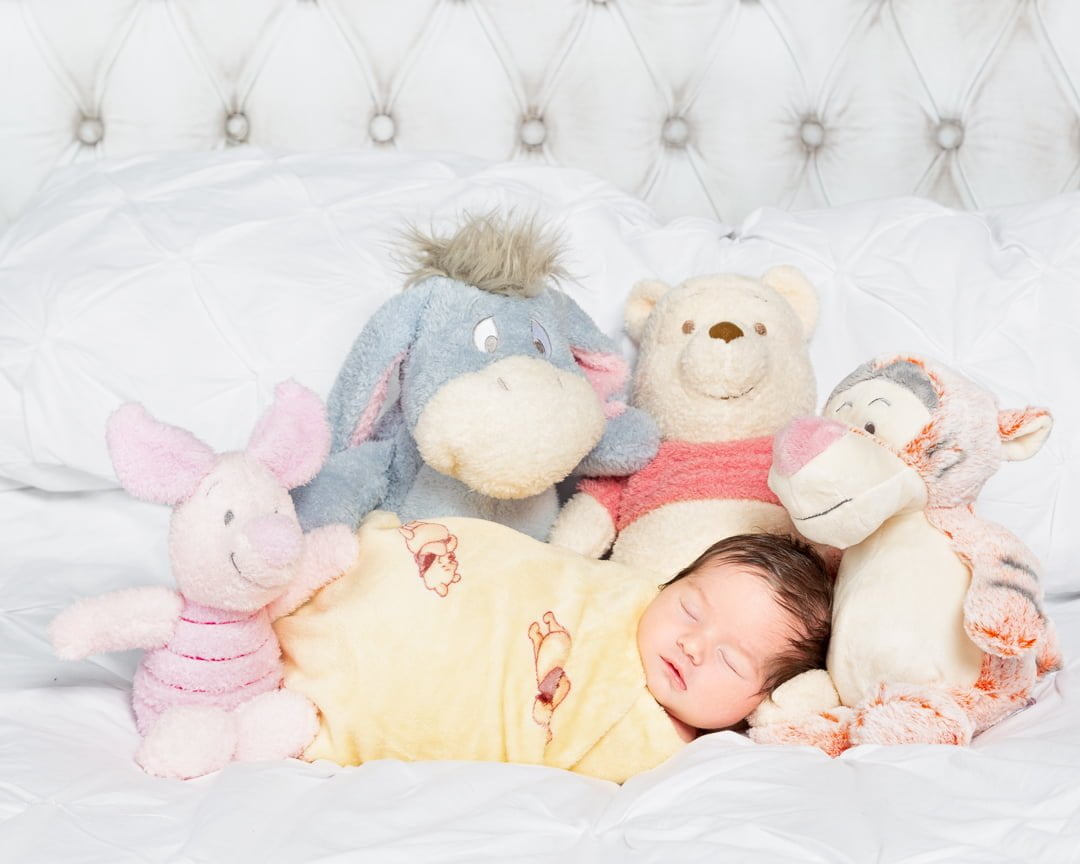 a newborn and a a host of Winnie the Pooh stuffed toys