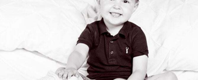 a big brother sits on a bed with his newborn sibling