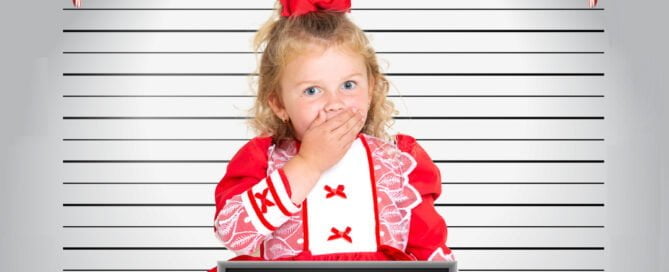 a little girl standing in front a mug shot board in a christmas themed photo