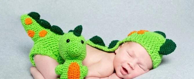 a newborn sleeping in a crocheted dinosaur costume