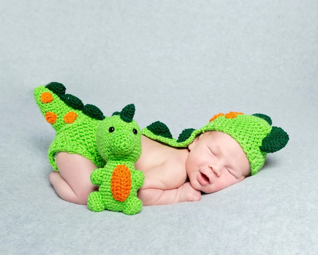 a newborn sleeping in a crocheted dinosaur costume