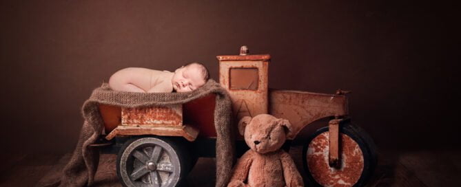a digitally composited image of a newborn sleeping in a tiny brown truck