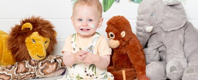a smiling little boy in a jungle themed cake smash photo shoot