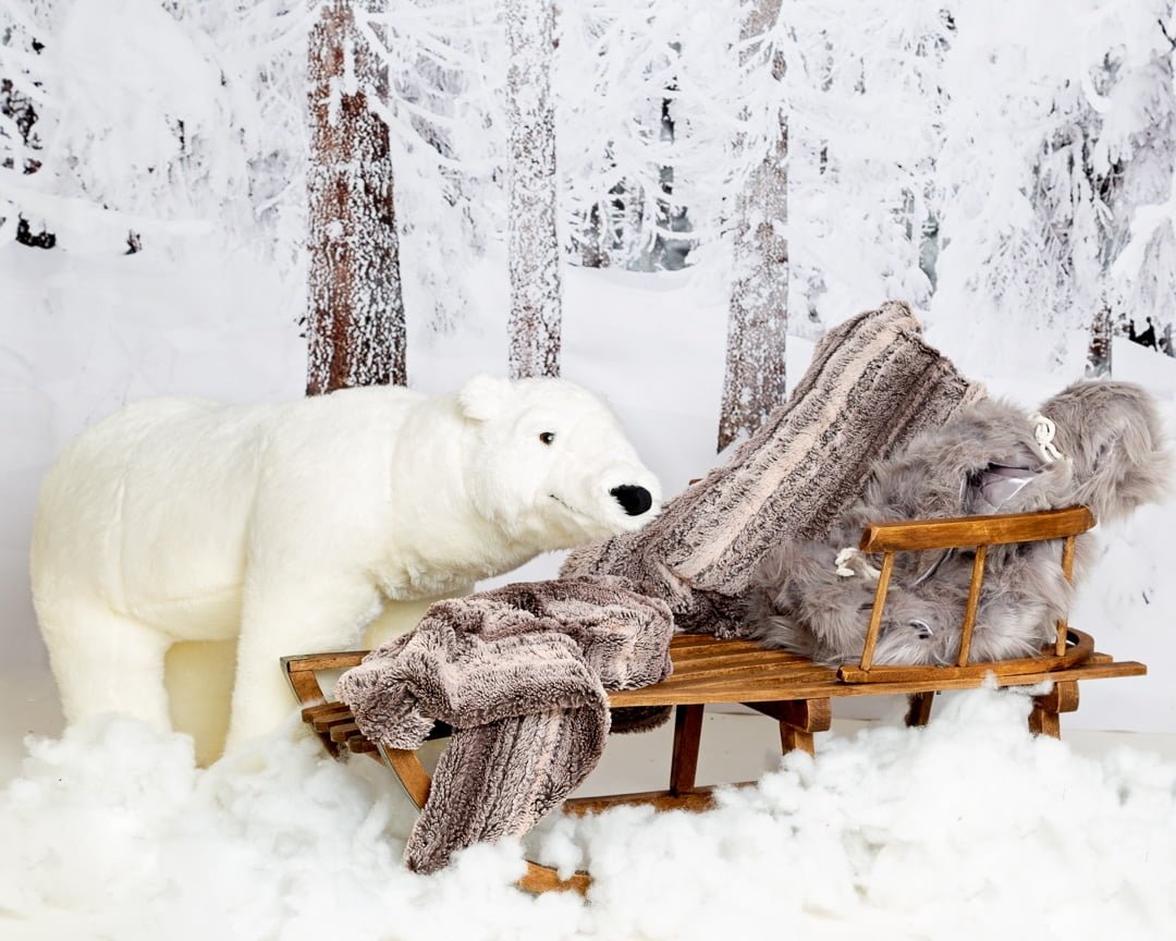 a snow themed christmas photo shoot set with a giant polar bear toy and wood sledge