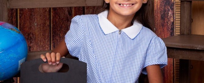 a little girl poses with a sign saying 2023 at a school themed photo shoot