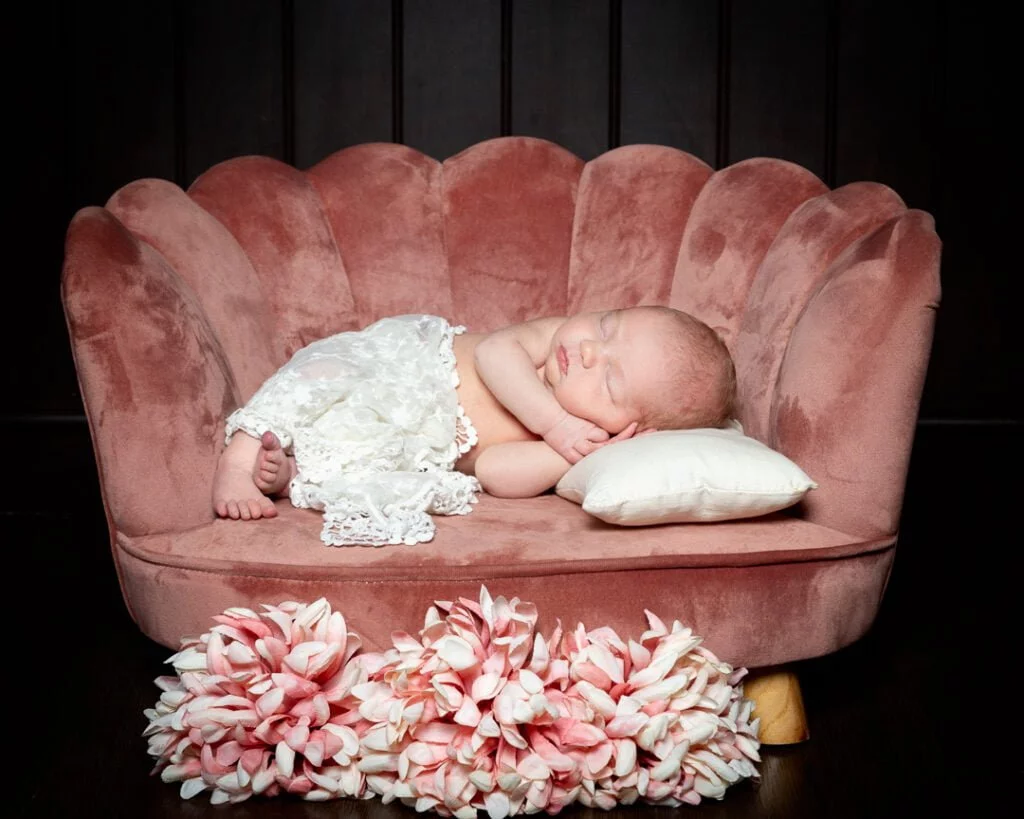 Newborn Photography East Grinstead West Sussex a newborn with a lace wrap sleeping in a small pink chair