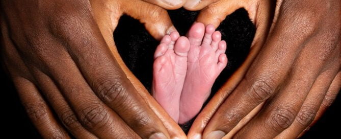 a newborn's feet surrounded by its parents hands in a heart shape