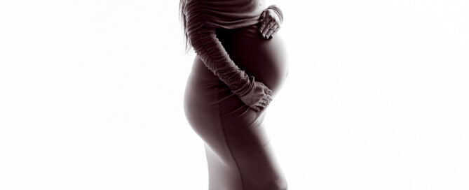 a black and white silhouette of a pregnant woman in a fitted dress