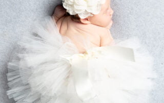 a sleeping newborn in a giant white fluffy tutu