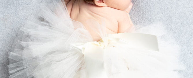 a sleeping newborn in a giant white fluffy tutu
