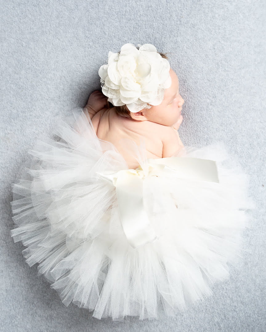 a sleeping newborn in a giant white fluffy tutu