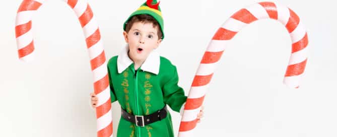 a little boy dressed as Elf holding two giant candy canes