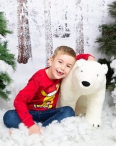 a little boy hugs a giant polar bear toy at a mini Christmas session