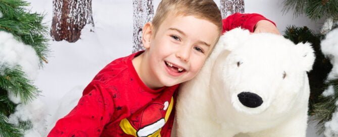 a little boy hugs a giant polar bear toy at a mini Christmas session