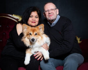 a man and woman pose with a fluffy corgi