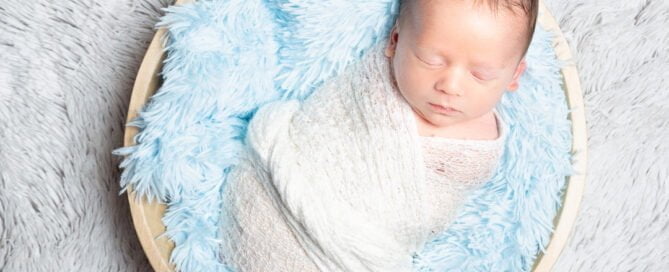 a newborn sleeping in a bowl filled with blue fluff
