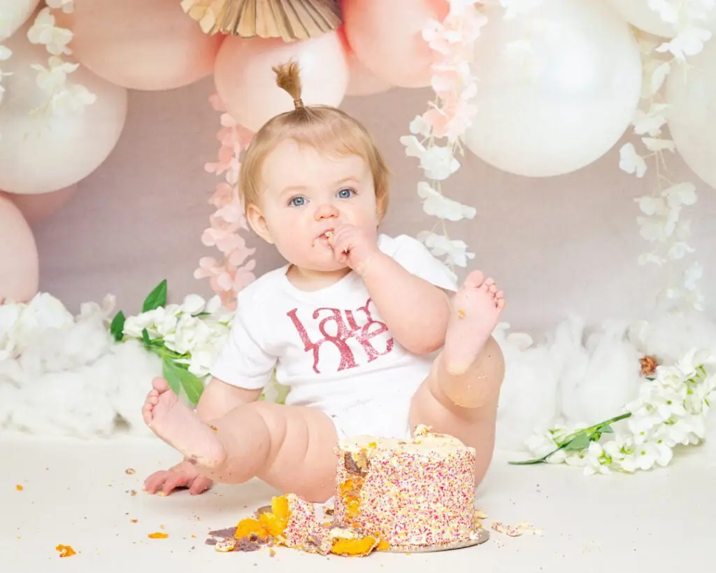 A little girl at a peach themed cake smash photo shoot