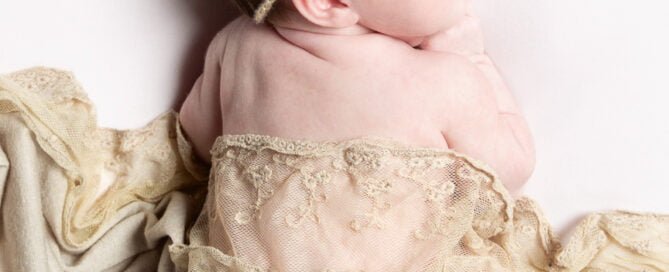 a sleeping newborn wrapped in neutral shades and lace fabrics