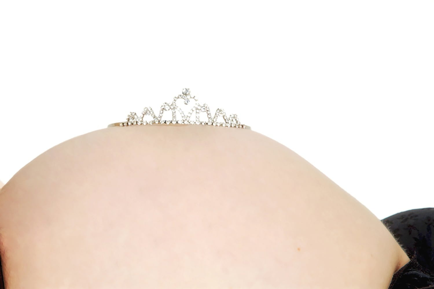 A pregnancy belly photographed with the mother lying down on her back, with a diamond tiara on top of the bump