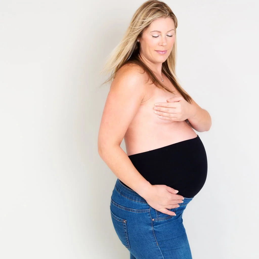Maternity Photography East Grinstead West Sussex a woman poses in her maternity jeans looking down to her bump