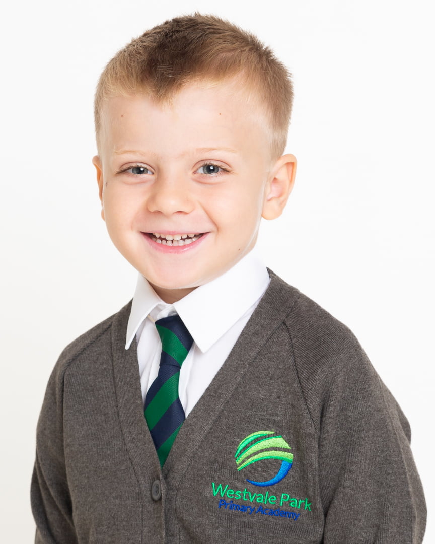 a little boy smiles for the camera at a studio school photo shoot