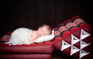 a newborn sleeping wrapped in white on a Thai bed mat from a client's holiday