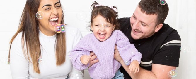 a family pose for a photo in my East Grinstead studio in a cloud of bubbles