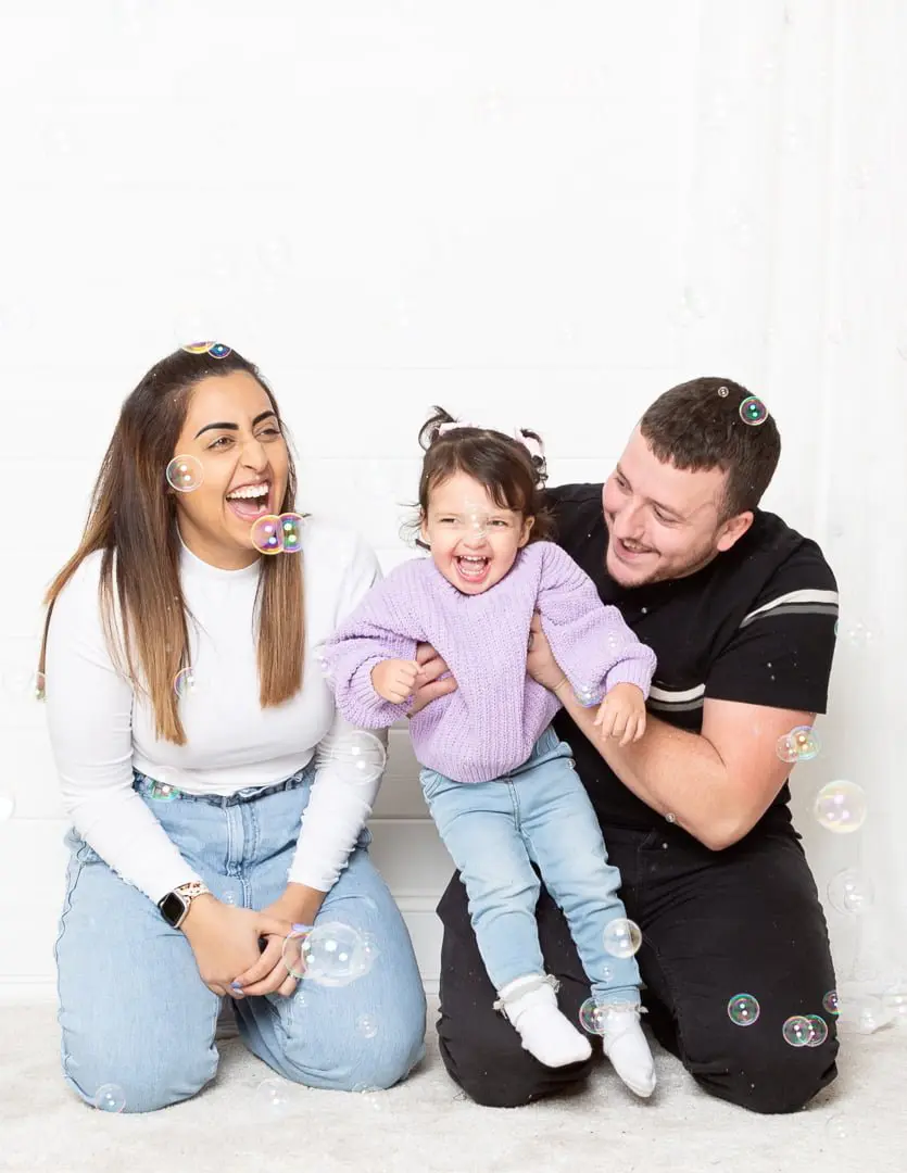 a family pose for a photo in my East Grinstead studio in a cloud of bubbles
