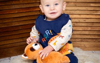 a baby and a red panda stuffed toy