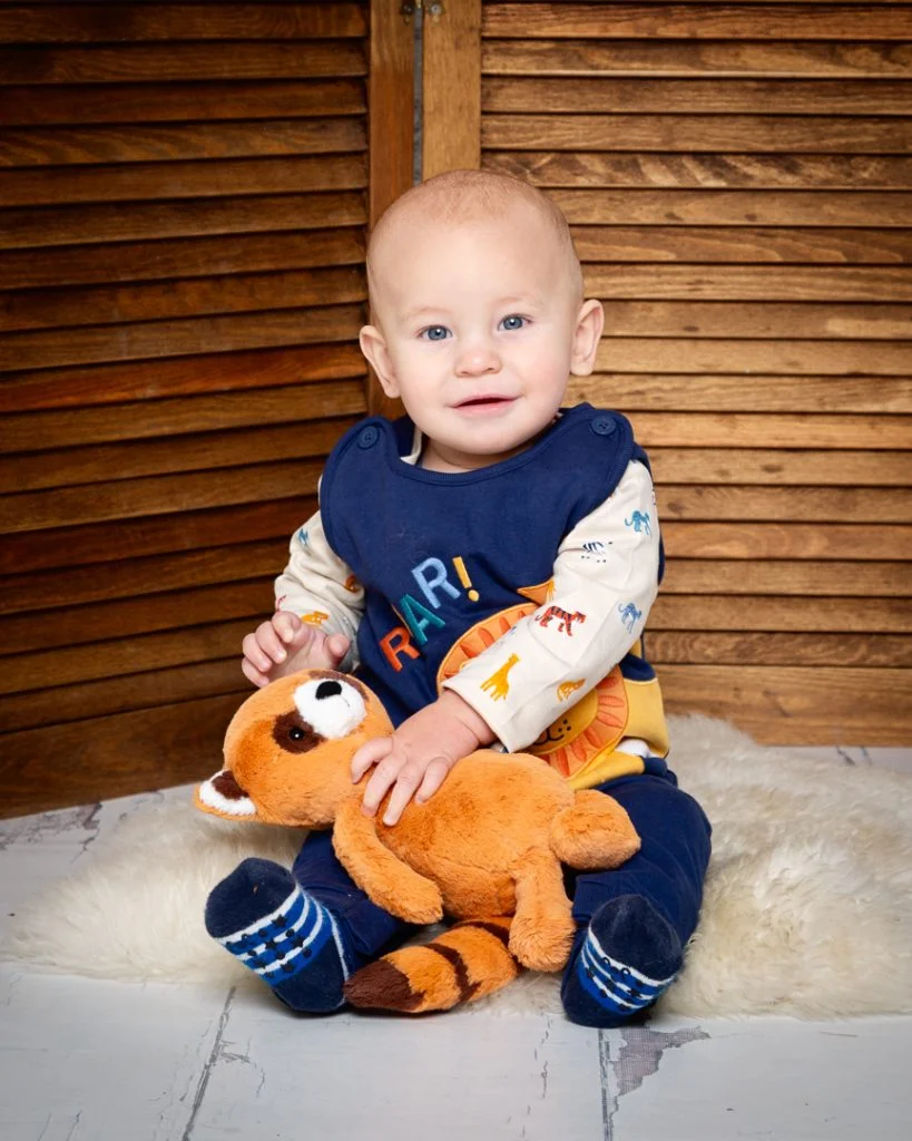 a baby and a red panda stuffed toy