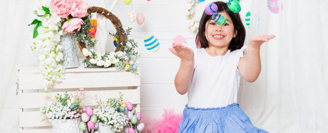 a little girl throws brightly coloured easter eggs into the air at an Easter photo shoot