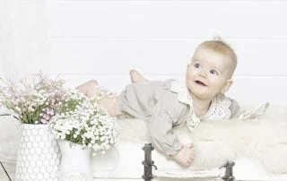 a baby in a cream outfit on my vintage suitcase prop