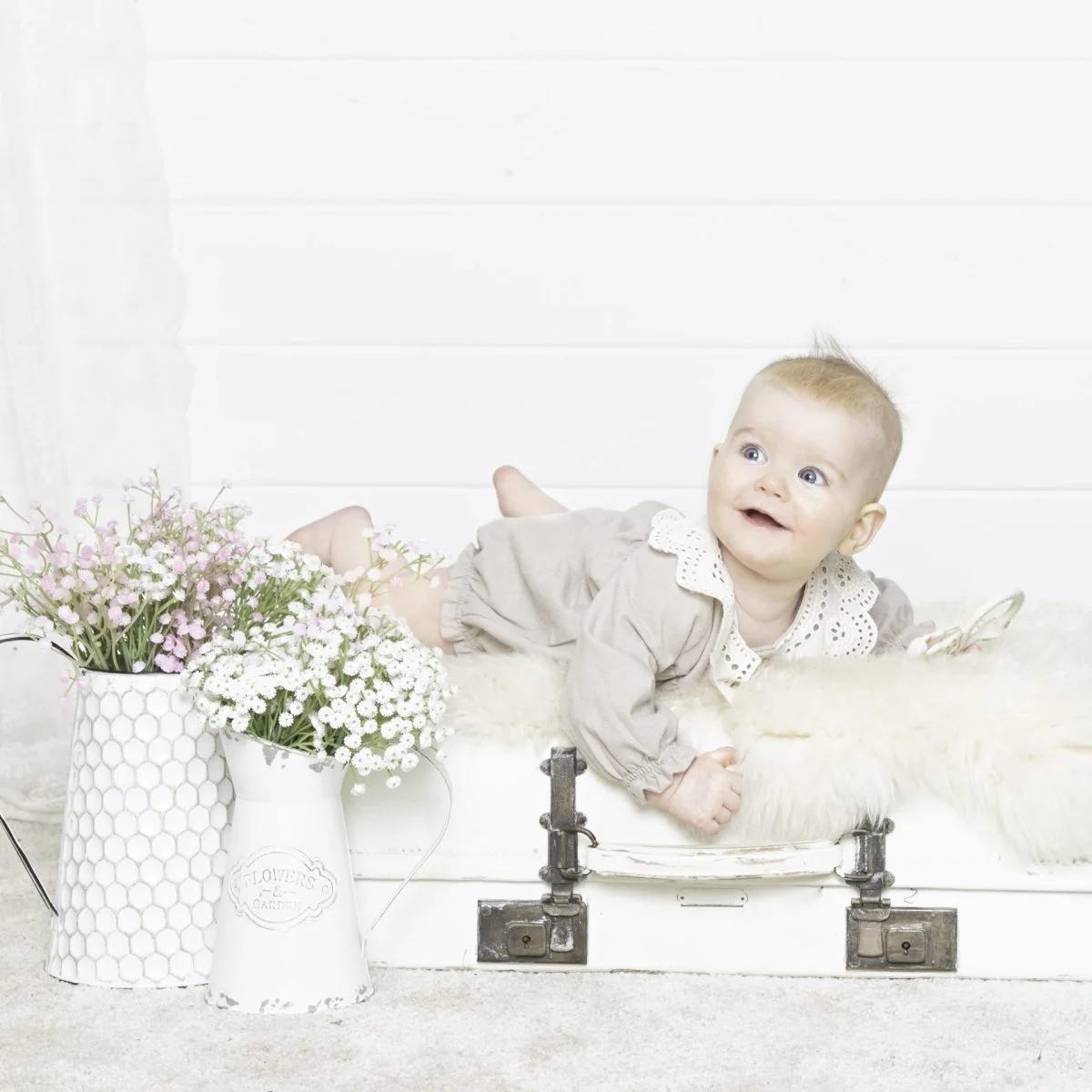 a baby in a cream outfit on my vintage suitcase prop