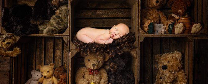 a digitally composited newborn image with a baby sleeping among crates of teddy bears