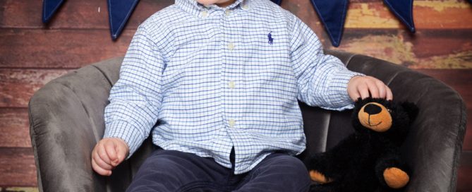 a baby and a stuffed bear toy at a photo shoot
