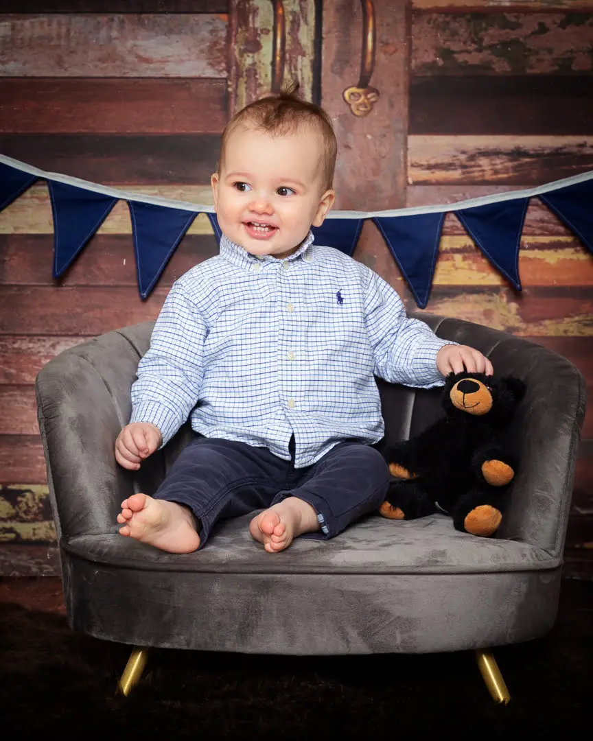 a baby and a stuffed bear toy at a photo shoot