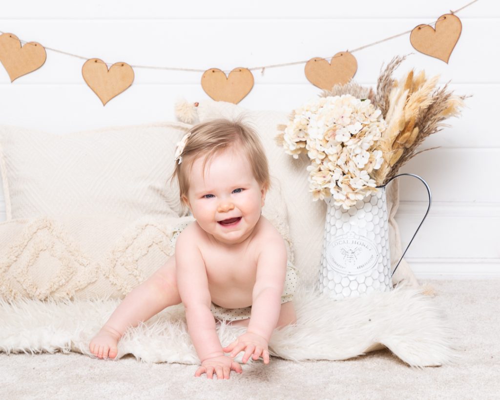 a baby photographed against a boho styled wooden heart backdrop