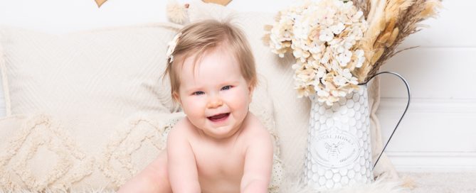 a baby photographed against a boho styled wooden heart backdrop