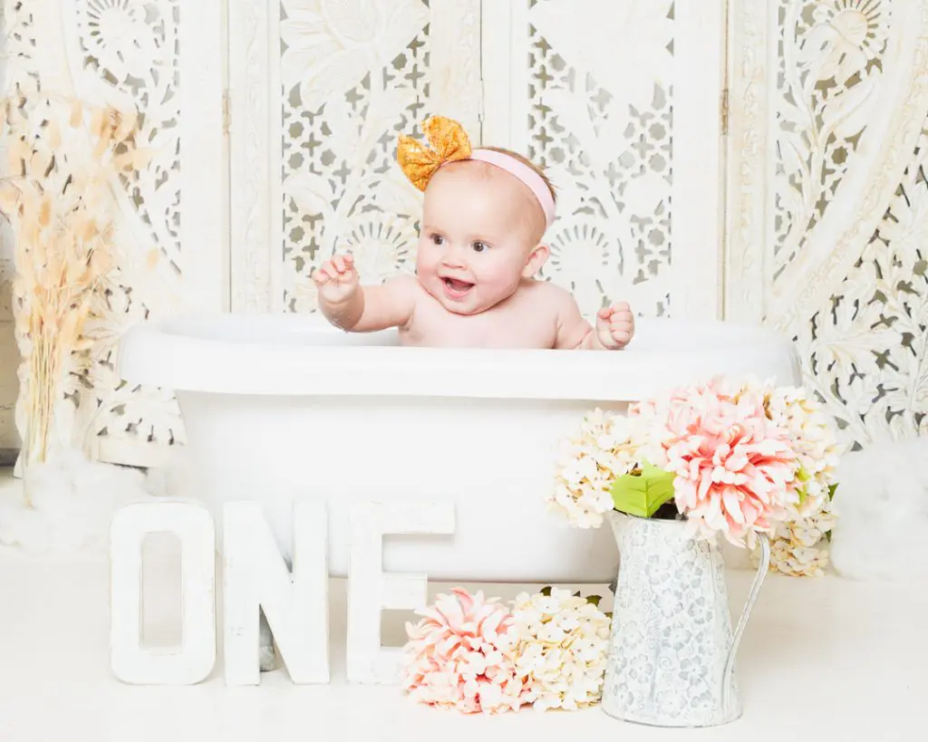 A happy little girl in a bathtub at her first birthday photo shoot