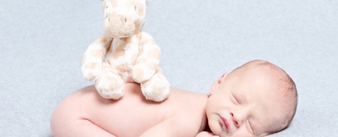a newborn with their first soft toy sitting on their back
