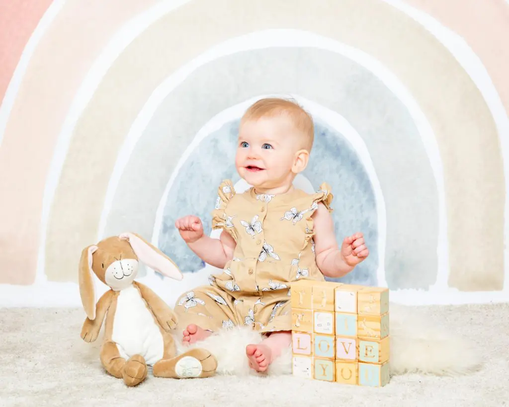 a little girl with Nutbrown Hare props in front of a rainbow backdrop