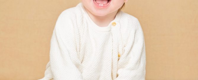 a baby against a cream background with a personalised toy