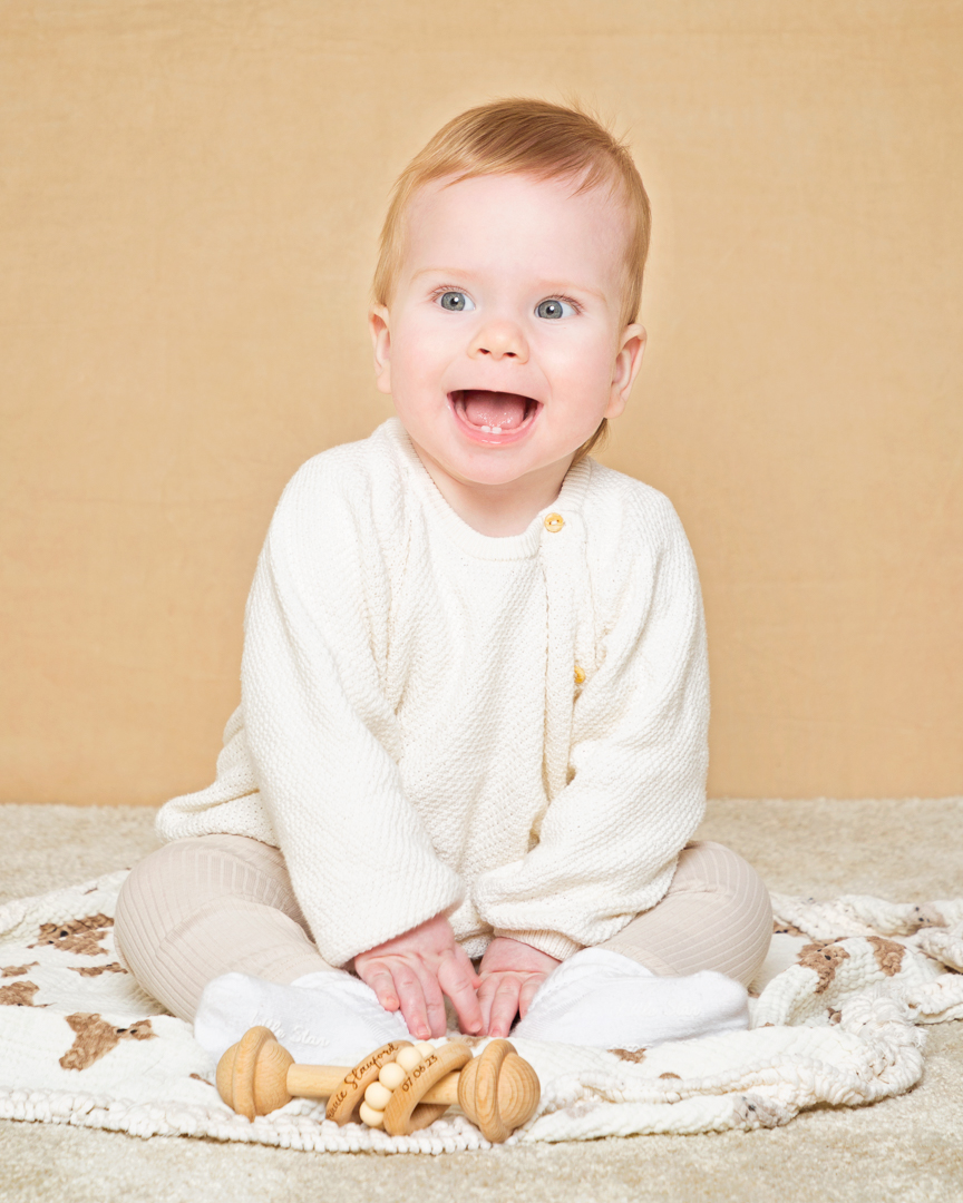 a baby against a cream background with a personalised toy