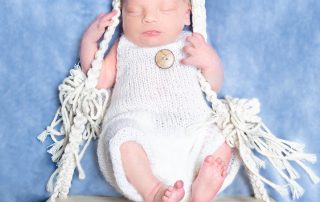 a sleeping newborn sitting on a swing and holding onto the strings