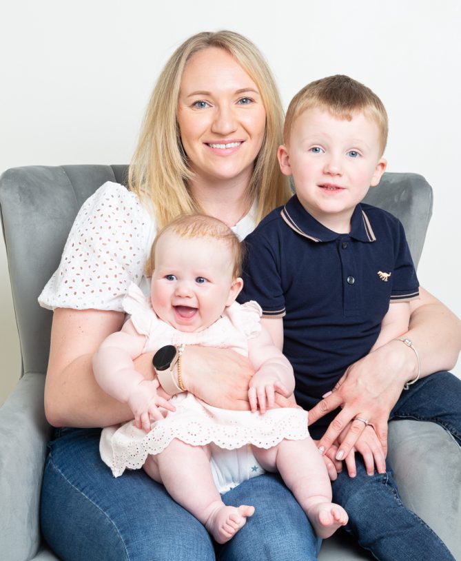 a mum poses on a chair with her two children on her lap