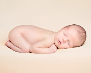 a peaceful sleeping newborn on a cream blanket