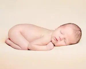 a peaceful sleeping newborn on a cream blanket