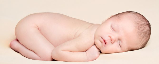 a peaceful sleeping newborn on a cream blanket